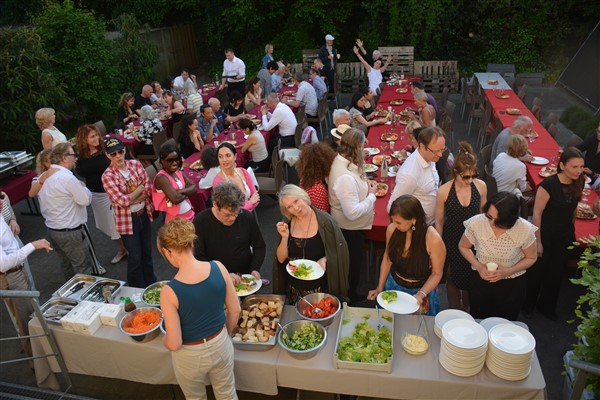 A group of people standing around a table full of food

Description automatically generated