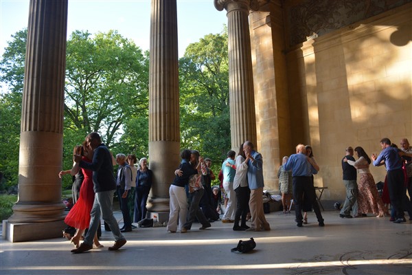 A group of people dancing in front of a building

Description automatically generated